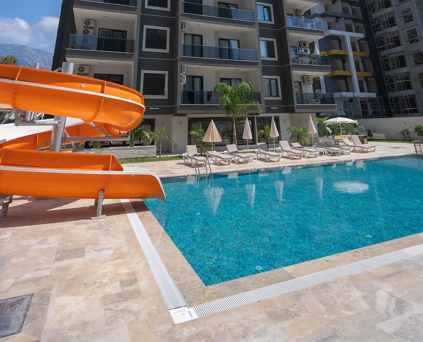 The pool with a water slide and sun loungers in the grounds