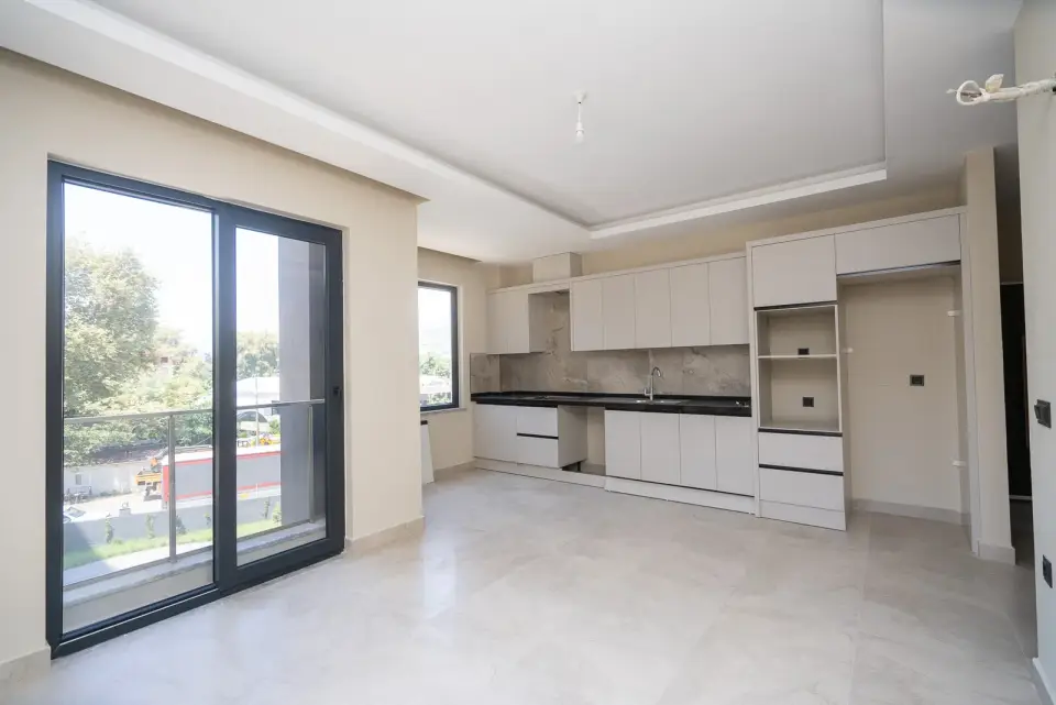 A living room with a kitchen and a balcony door