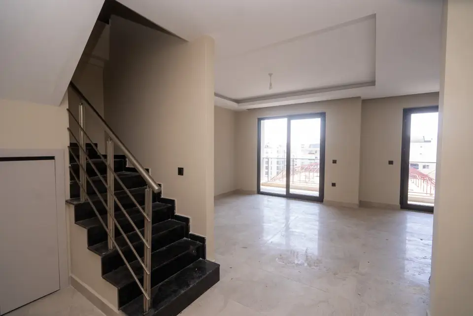 A penthouse living room with a staircase to the upper level