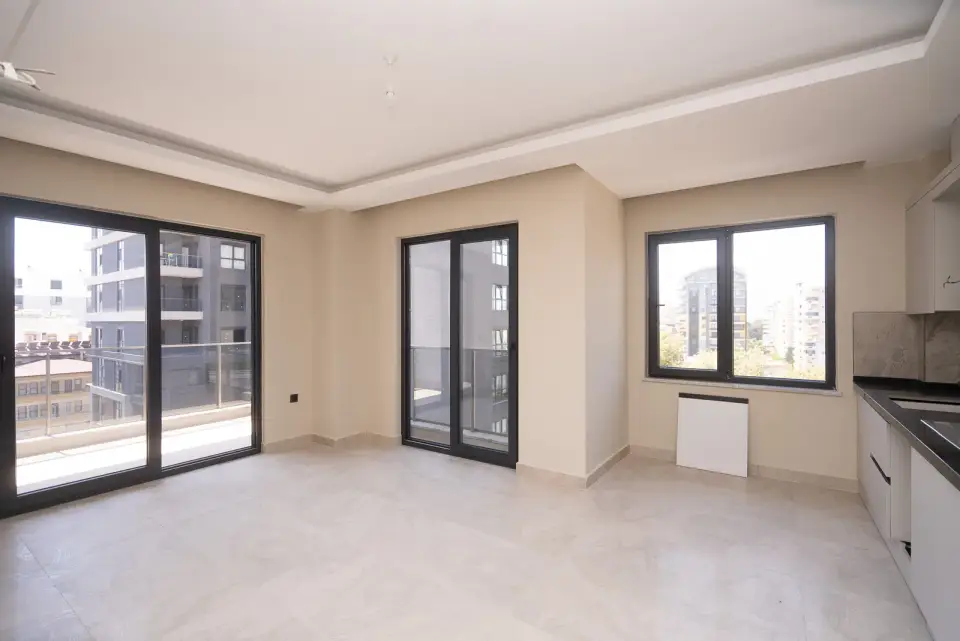 A living room with a kitchen and two balcony doors